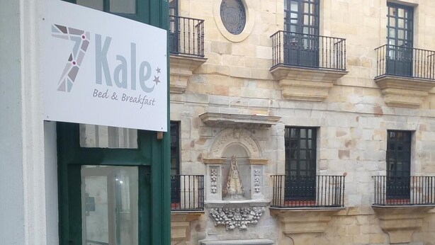 A building with a sign for 'Kale Bed & Breakfast' and a traditional stone facade with a wooden door and barred windows. - 7 Kale Bed and Breakfast (Bilbao)