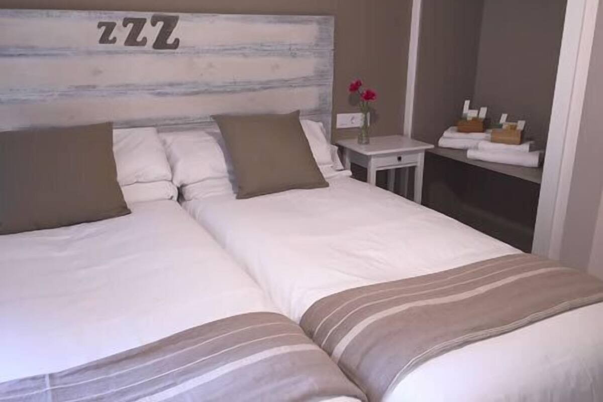 A double bed with a striped blanket, two pillows, and a headboard with the number '222'.