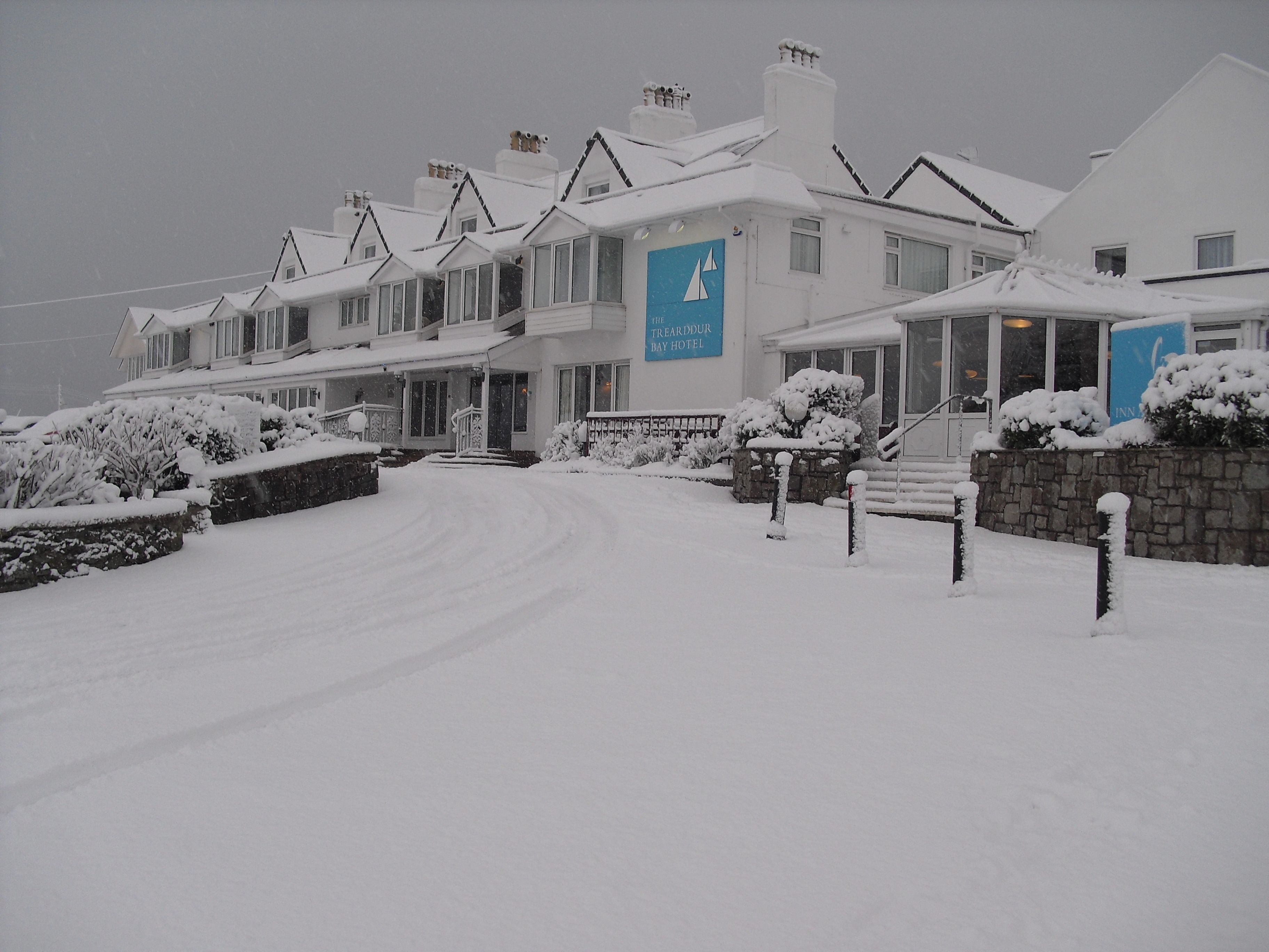 Uma fileira de casas brancas com uma placa indicando "The Trearddur Bay Hotel" no centro.