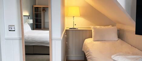 A bedroom with a bed, a bedside table with a lamp, a wardrobe, and a mirror.