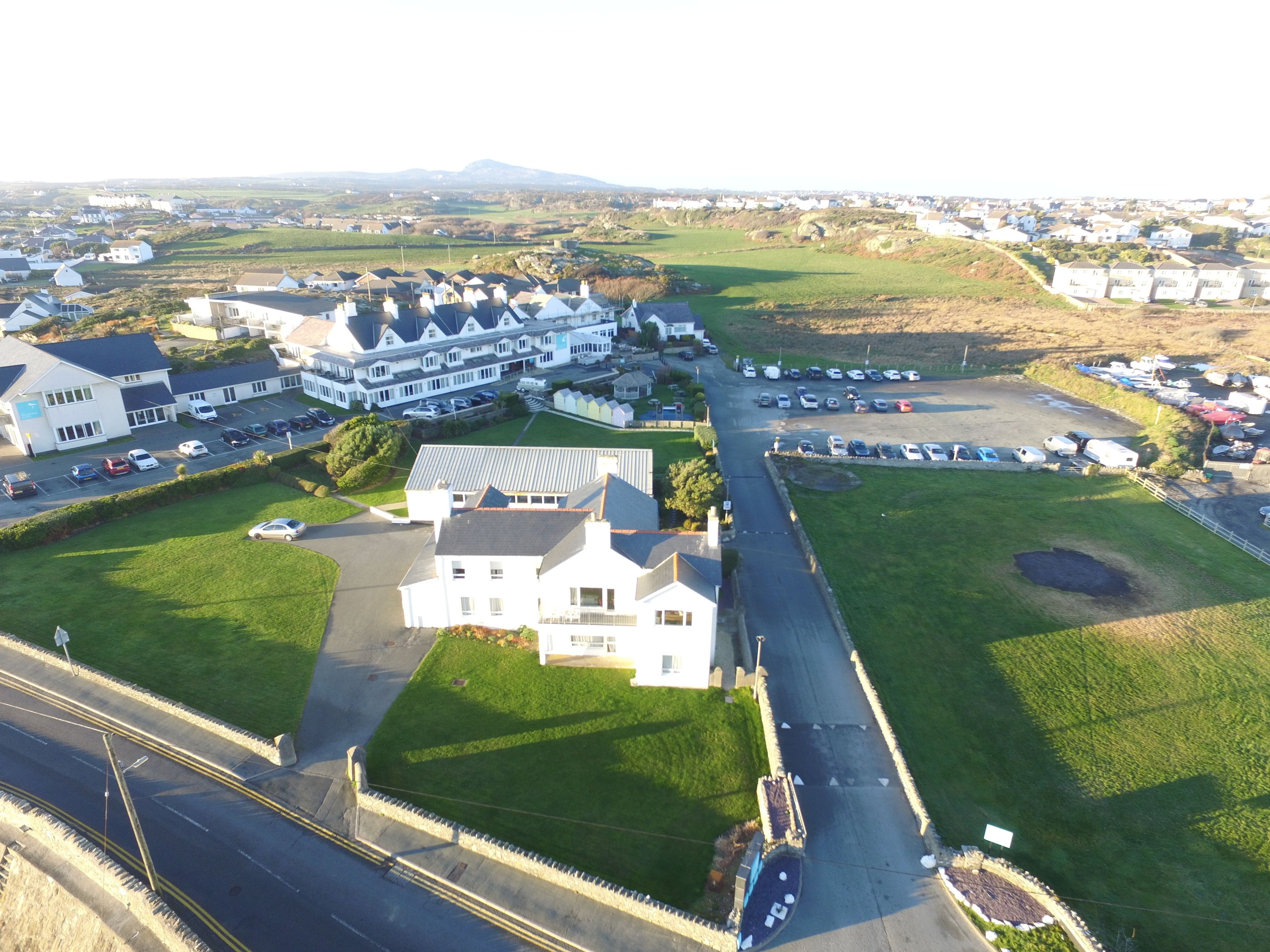 An aerial view of a residential area with houses, a parking lot, and a road.