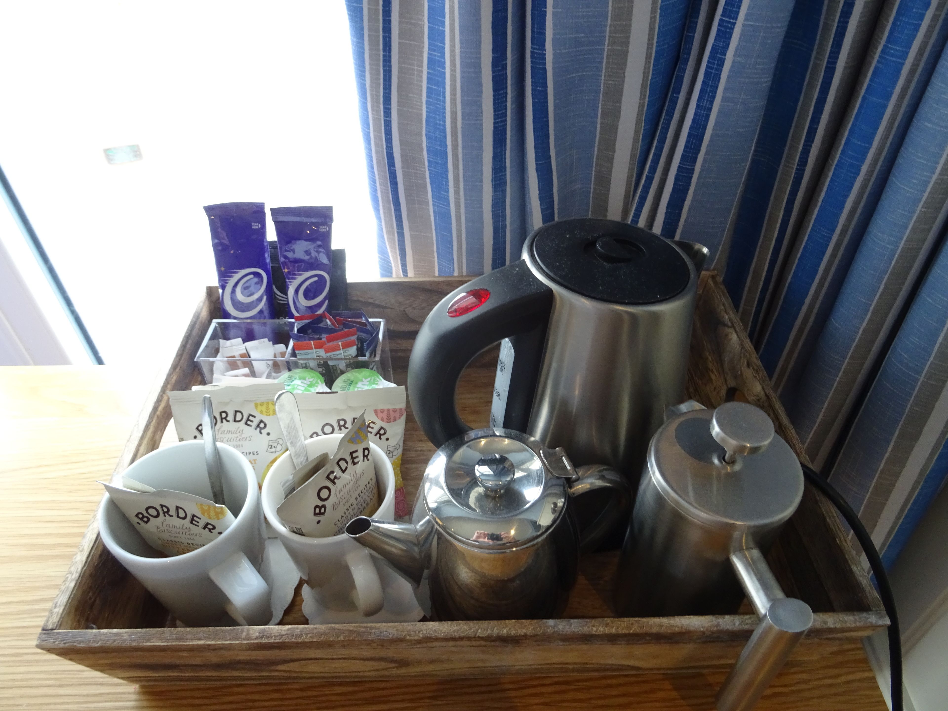 A tray with coffee-making equipment and branded coffee packets.