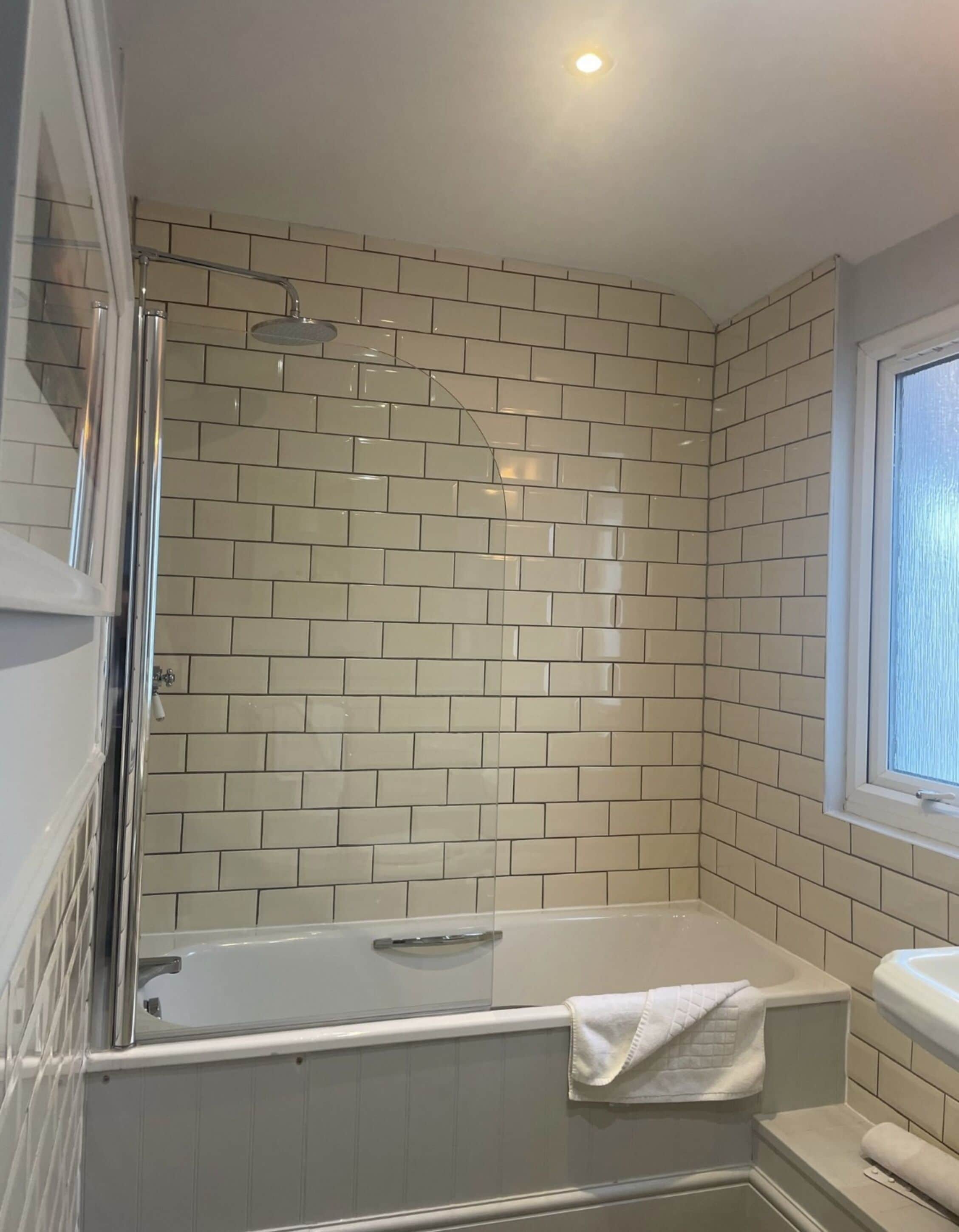 A bathroom with a bathtub, a shower, and a window.
