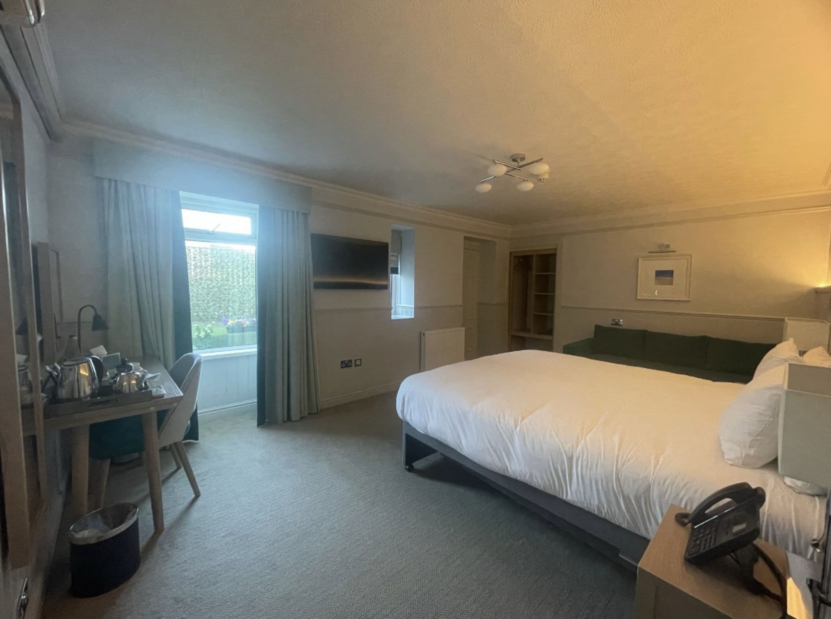 A hotel room with a bed, desk, chair, and a telephone.