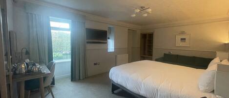 A hotel room with a bed, desk, chair, and a telephone.