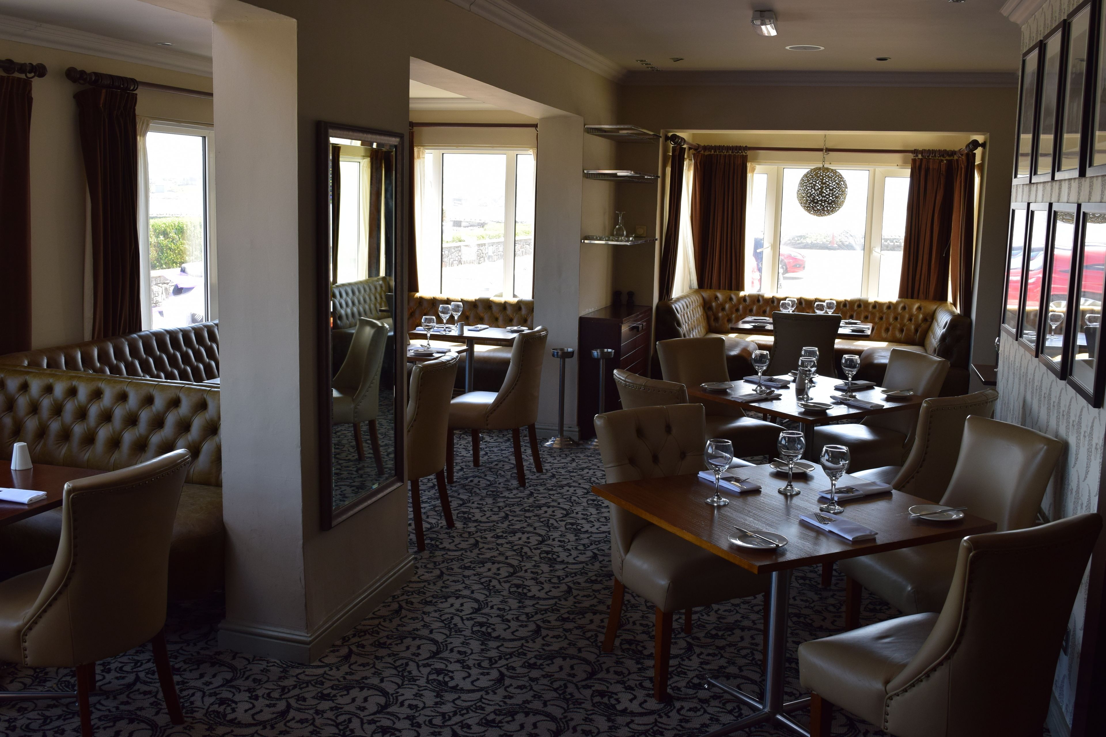 A restaurant with a high ceiling, leather seating, and a patterned floor.