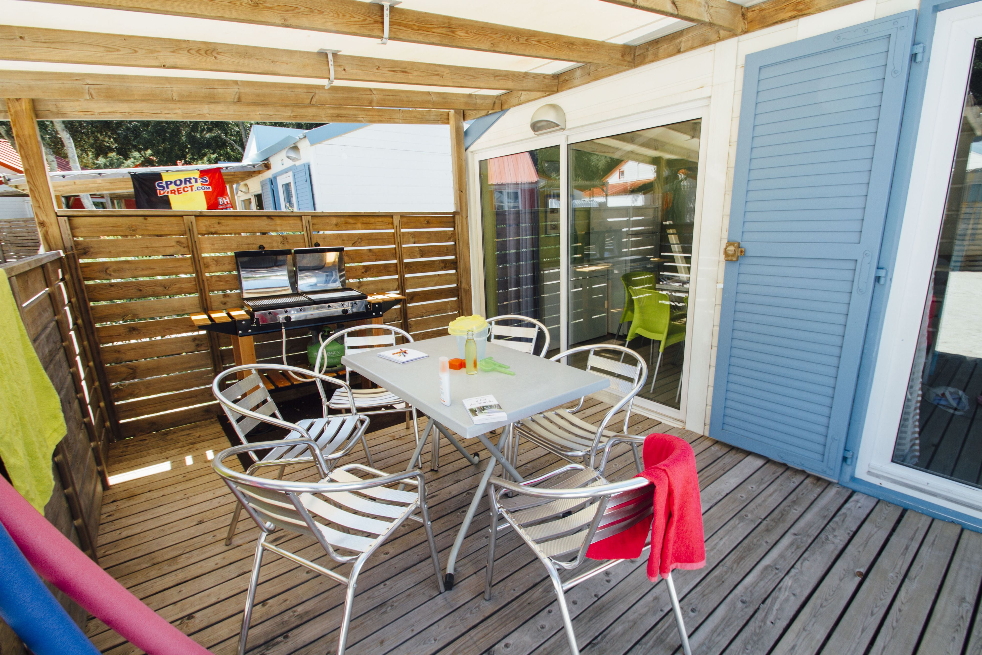 Un patio al aire libre con mesa, sillas, una parrilla y un ventanal corredero.