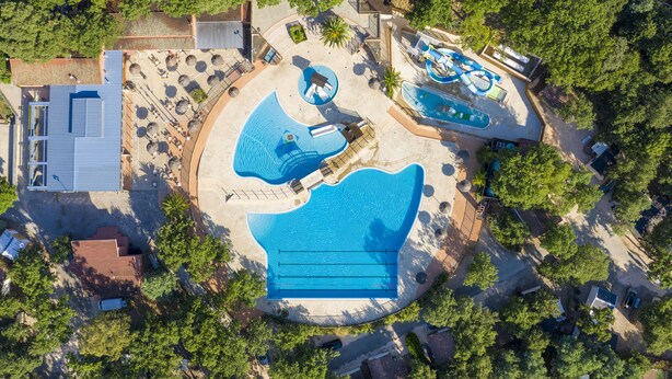 An aerial view of a resort with multiple swimming pools, sun loungers, and a large building with a flat roof. - Camping Le Bois Fleuri (Argelès-sur-Mer)
