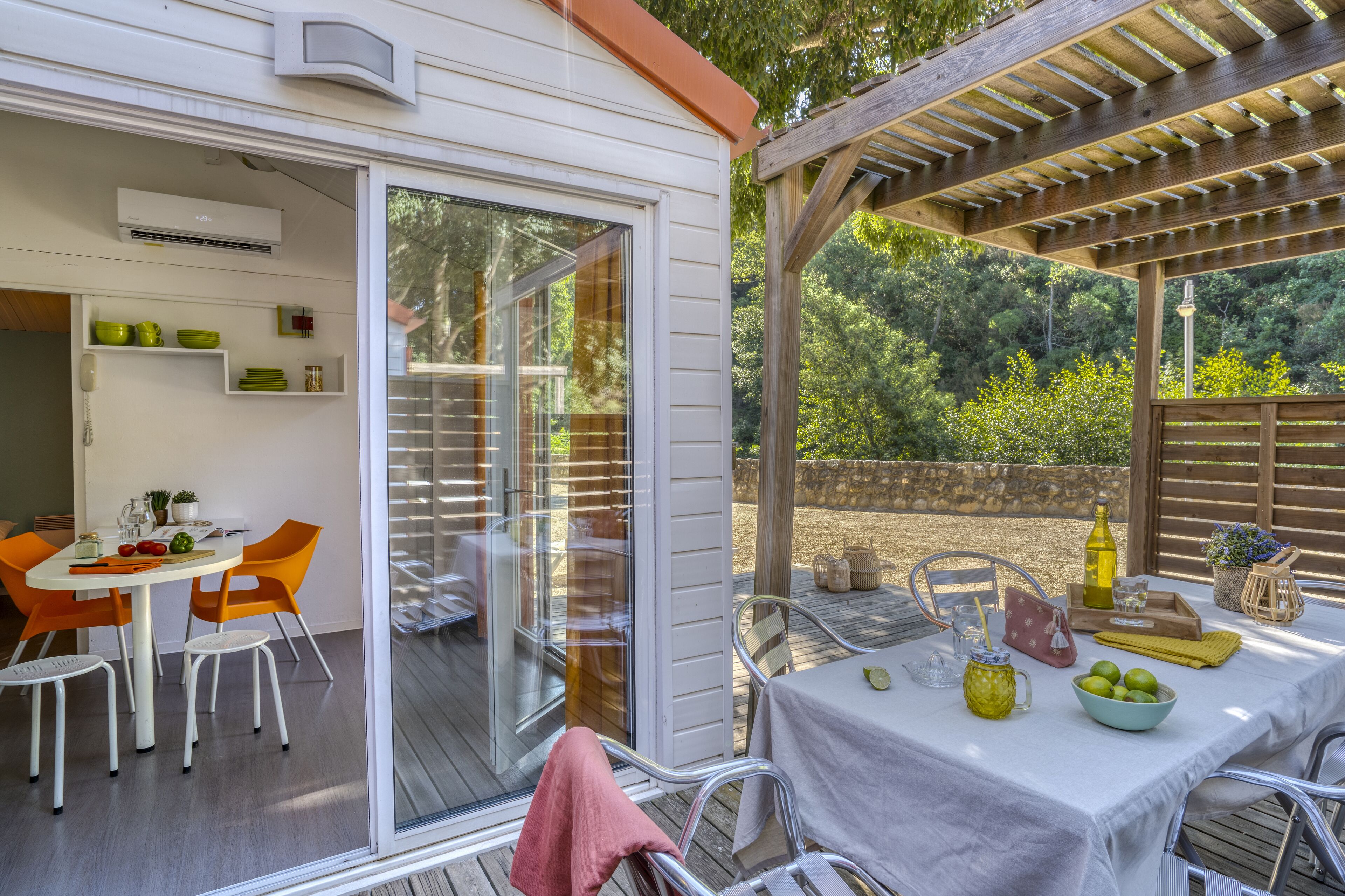 A patio with a table set for dining, a pergola, and a view of the surrounding greenery.