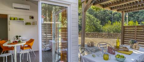 A patio with a table set for dining, a pergola, and a view of the surrounding greenery.