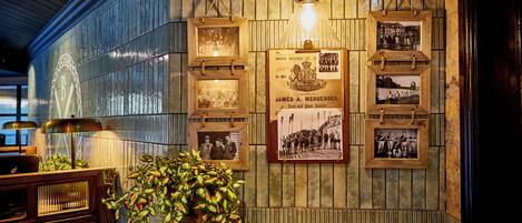 A bar area with wooden furniture, framed photographs on the wall, and a hanging light fixture.