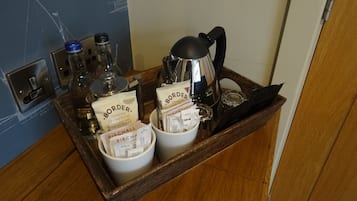 A tray with a coffee maker, two mugs labeled 'Border', and various small containers.