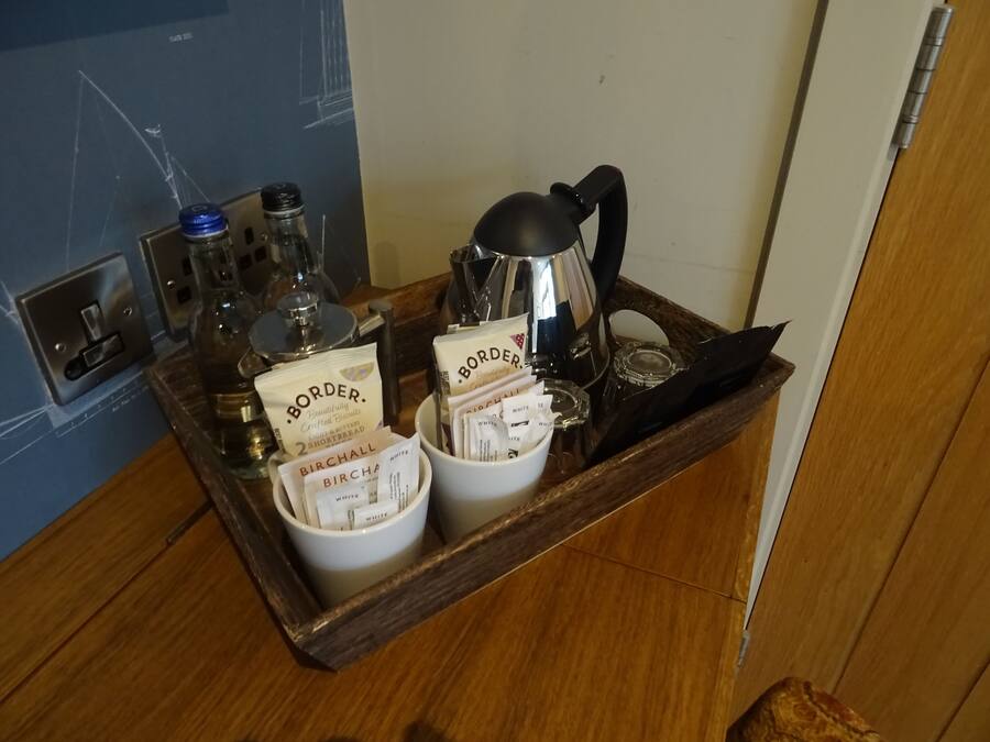 A tray with a coffee maker, two mugs labeled 'Border', and various small containers.