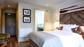 Habitación de hotel con una cama, una puerta de madera, un radiador y una pared con cuadros.