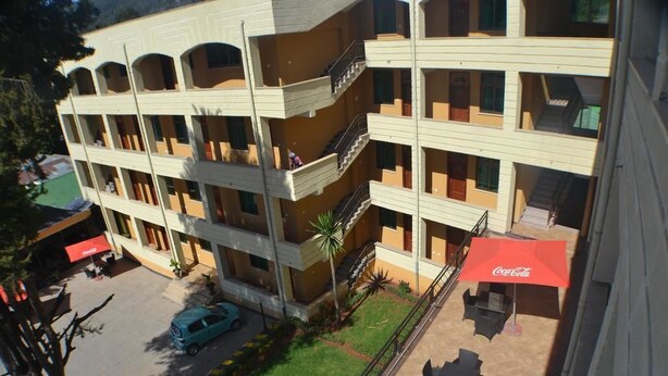 A multi-story hotel with balconies, outdoor seating, and a parked car. - Fasil International Hotel (Addis Ababa)