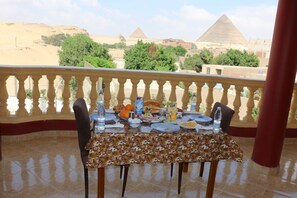 A table set for dining with a view of pyramids in the background. - Ramosa Guest House (Giza)