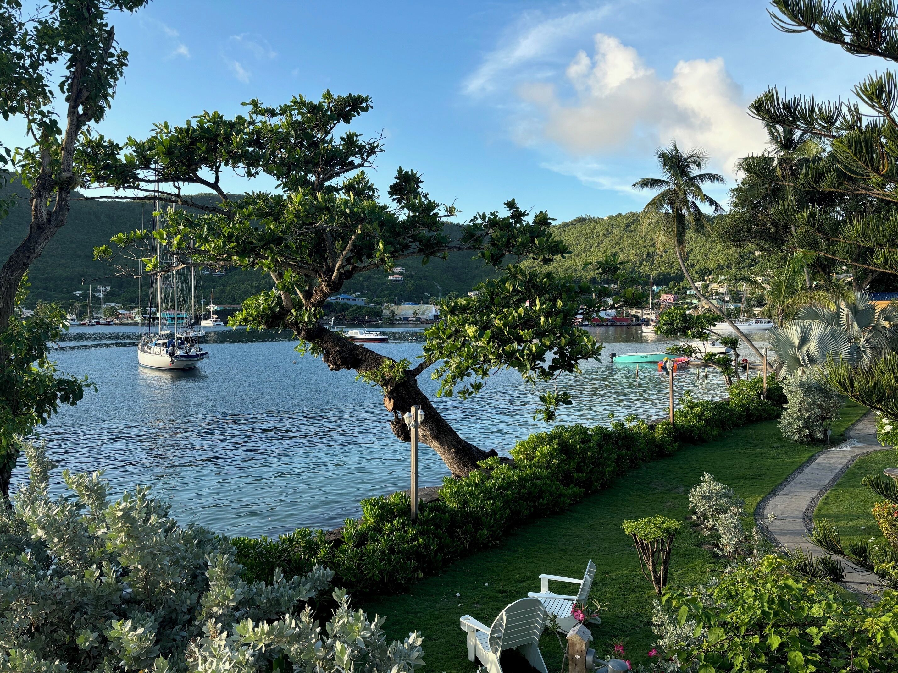 A serene lakeside setting with a boat dock, lush greenery, and a pathway leading to outdoor seating.