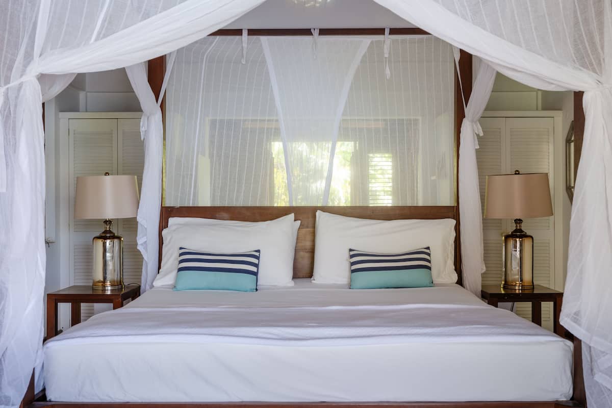 A bed with white linens, two bedside tables with lamps, and a canopy over the bed.