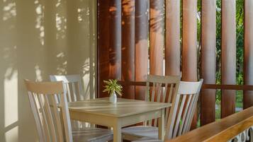 A wooden table with four chairs, a small potted plant, and a wooden bench.