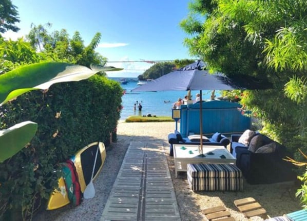 Uma área de estar à beira-mar com vista para o mar, um espaço de estar coberto e um suporte para pranchas de surf.