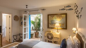 Habitación de hotel con cama, mesita de noche, lámpara, mapa en la pared y plantas en macetas.