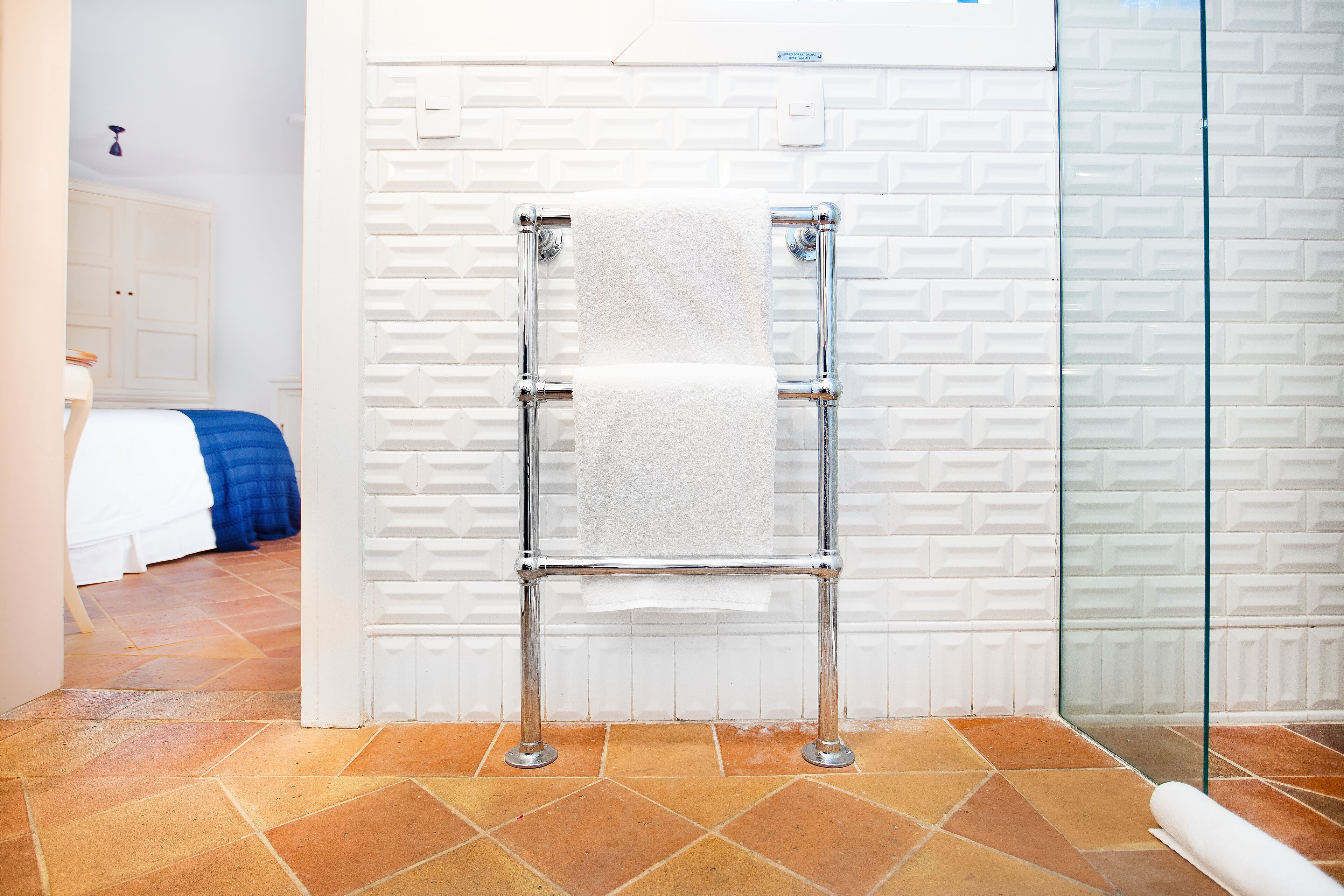 A bathroom with a towel rack, a shower area, and a tiled floor.
