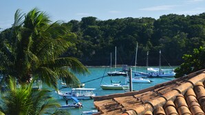 Escena costera con barcos amarrados cerca de una zona boscosa.