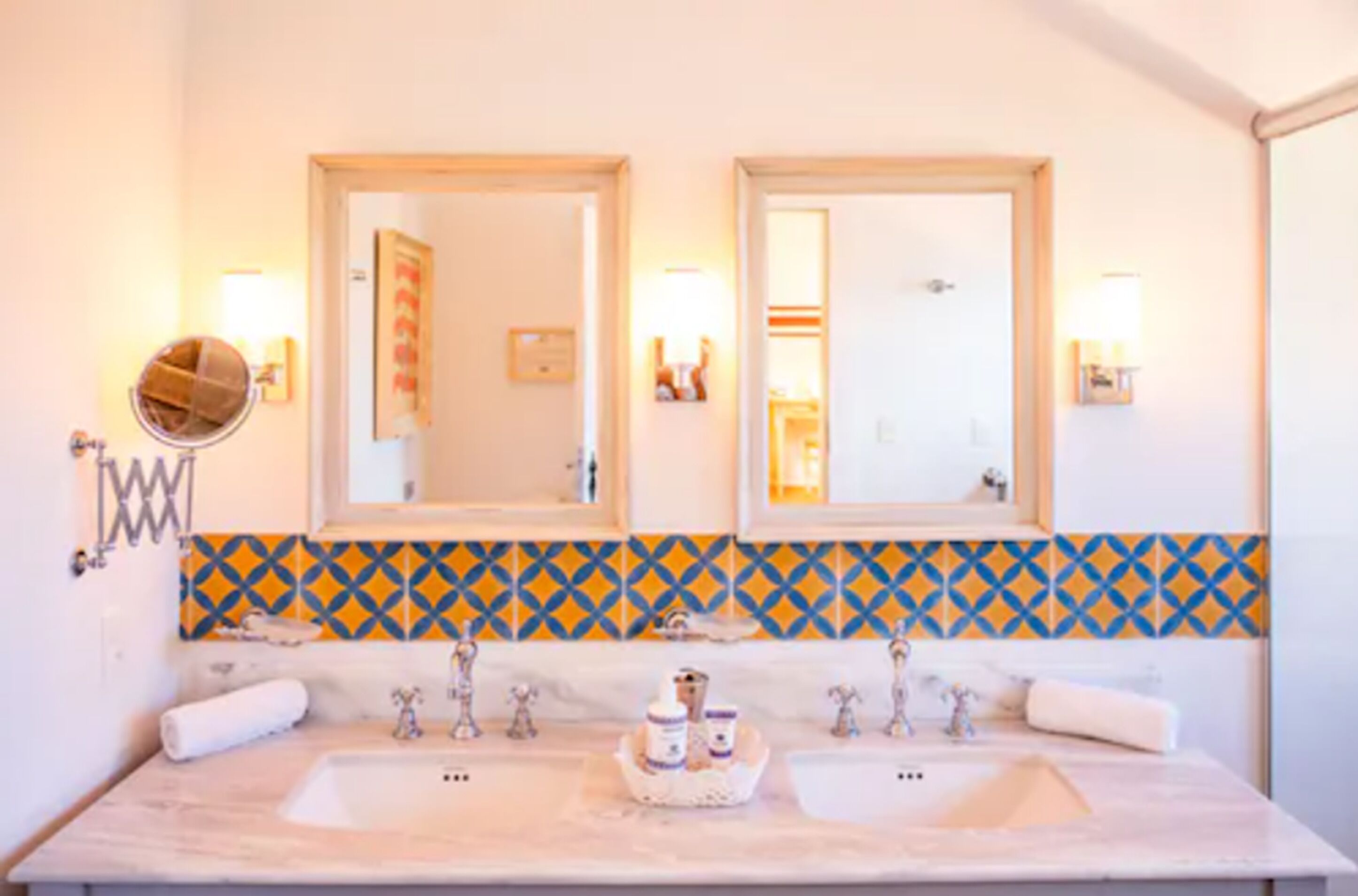 Une salle de bain avec deux lavabos, un miroir et un mur recouvert de carreaux décoratifs.