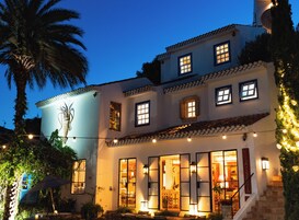 A two-story building with multiple windows, a staircase, and outdoor seating.
