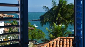 A coastal view from a balcony with a tiled roof, palm trees, and boats on the water. - Vila da Santa Hotel Boutique & Spa (Búzios)