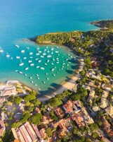 An aerial view of a coastal town with a marina, houses, and a beach.