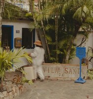 Una persona caminando frente a un edificio con un letrero que dice 'VILA SANTA DA'.