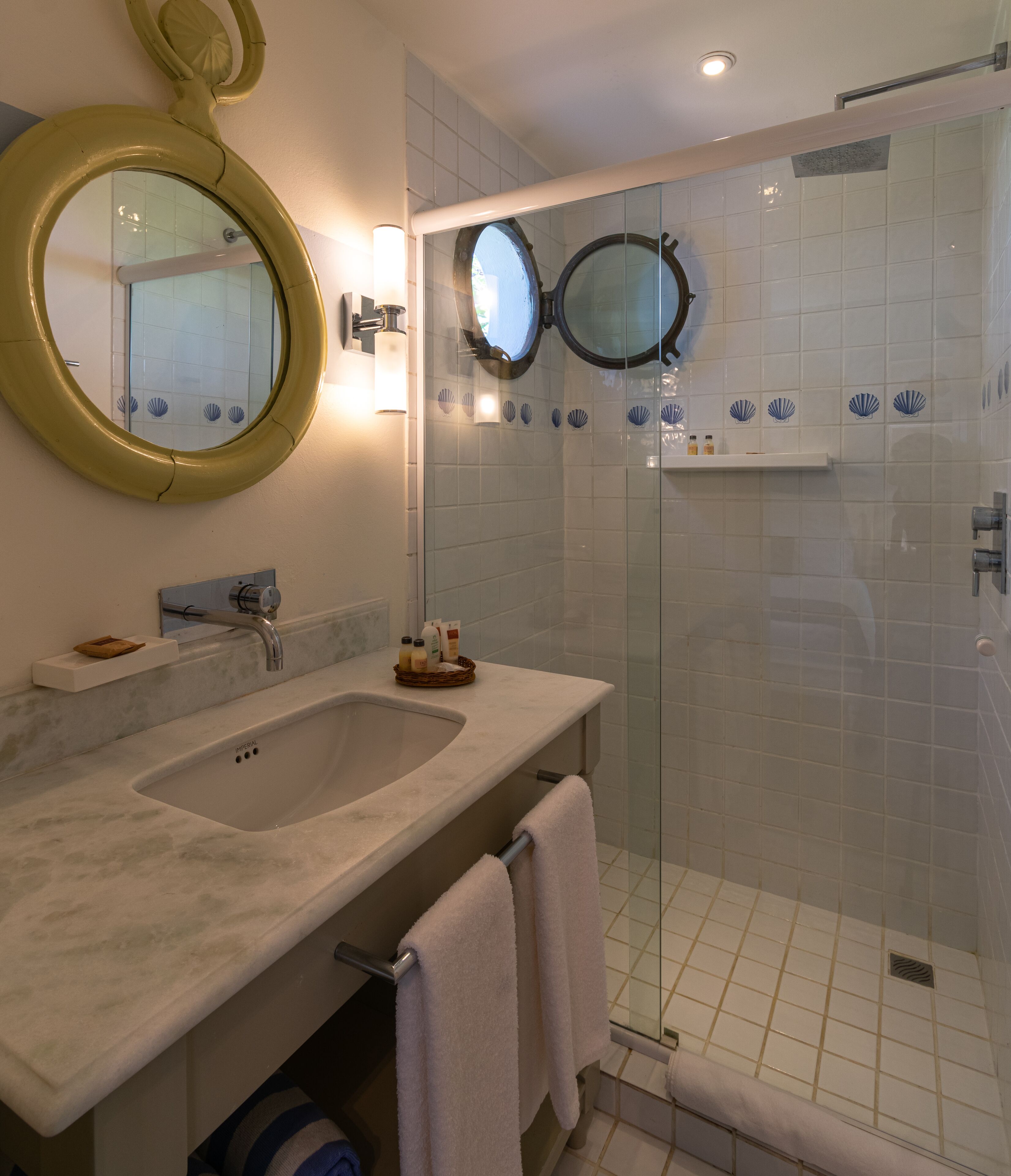 A bathroom with two sinks, a large mirror, and a glass-enclosed shower area.