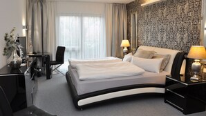 A modern hotel room with a curved bed, a desk, and a chair. - Hotel Villa Casamia - Adult Only (Schmalkalden)