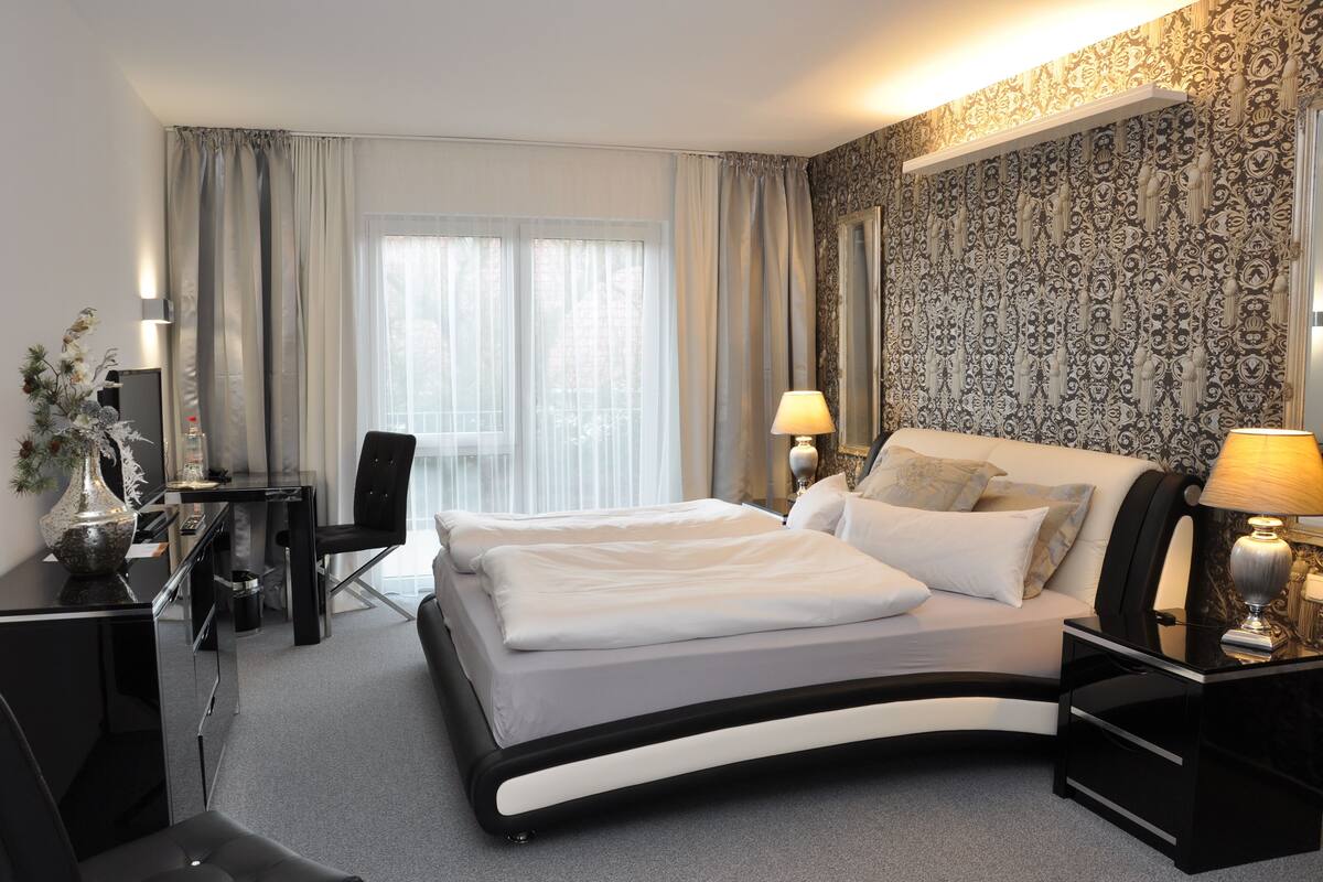 A modern hotel room with a curved bed, a desk, and a chair.