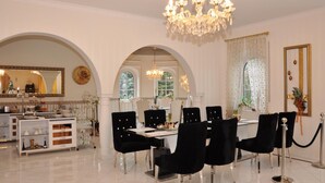 A formal dining room with a chandelier, black upholstered chairs, and a white table. - Hotel Villa Casamia - Adult Only (Schmalkalden)