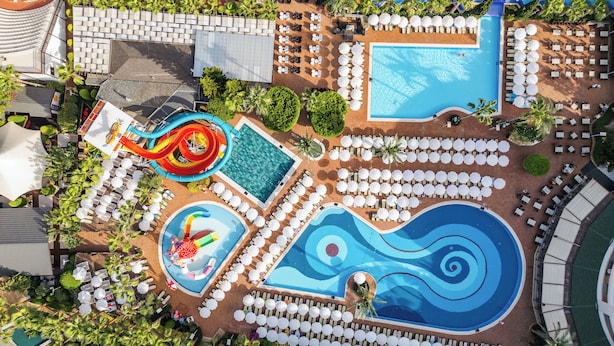 An aerial view of a resort with multiple swimming pools, water slides, and sun loungers arranged around the pools.
