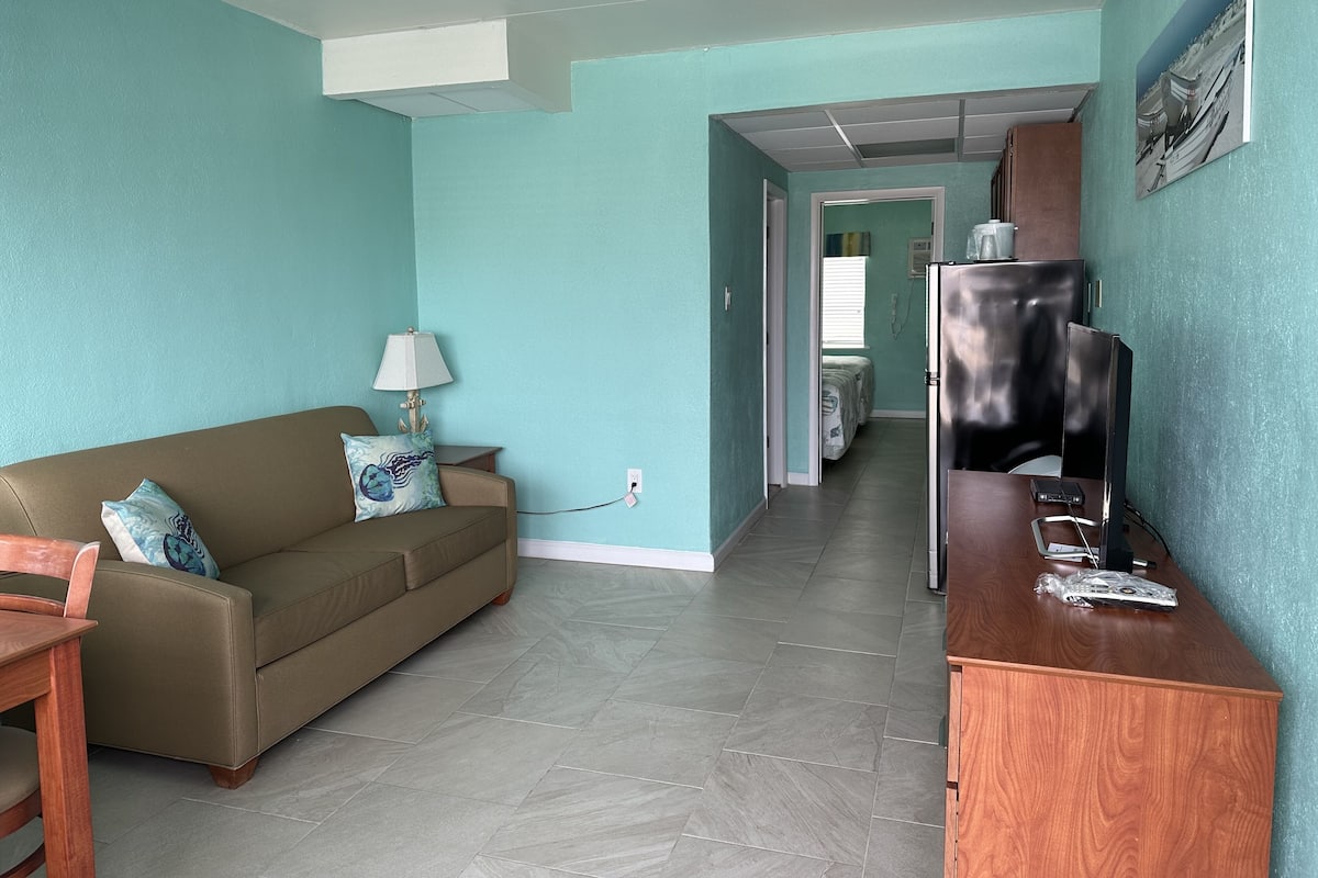Una sala de estar con sofá, mesa, lámpara y mueble para televisor.