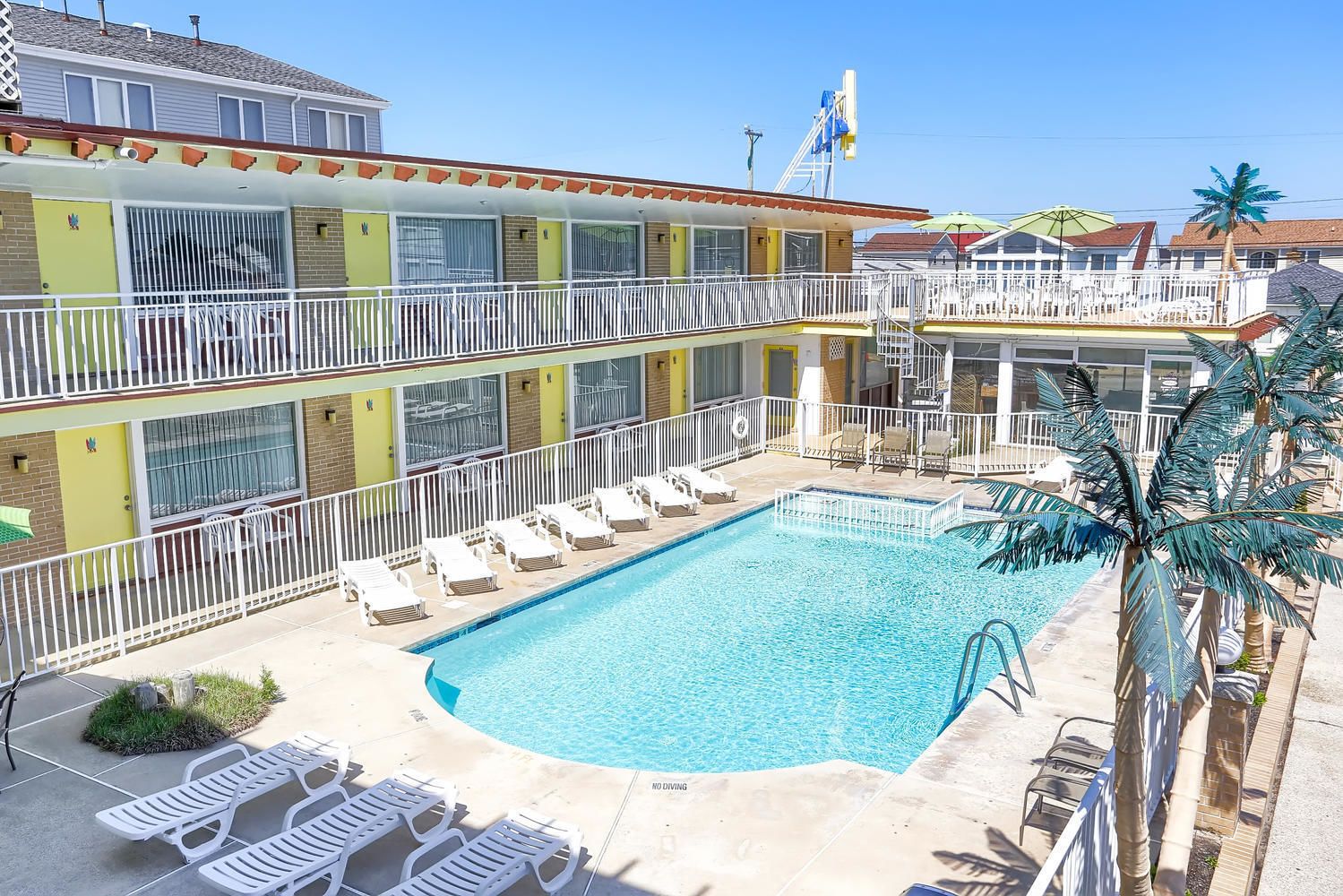 A multi-story hotel with a pool area, including sun loungers and a no diving sign.