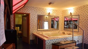 A bathroom with a large bathtub, a mirror, and a tiled wall.