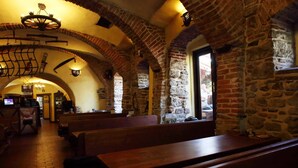 An interior with stone walls, wooden benches, and a chandelier.