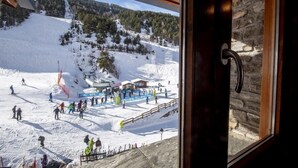 A ski resort with a wooden building, a ski lift, and a snowy landscape.
