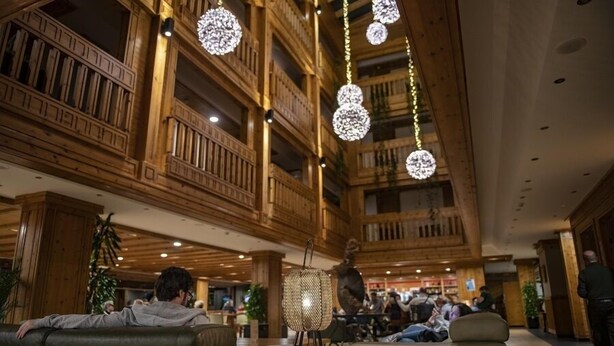 A spacious lobby with wooden architecture, a seating area, and hanging decorative lights.
