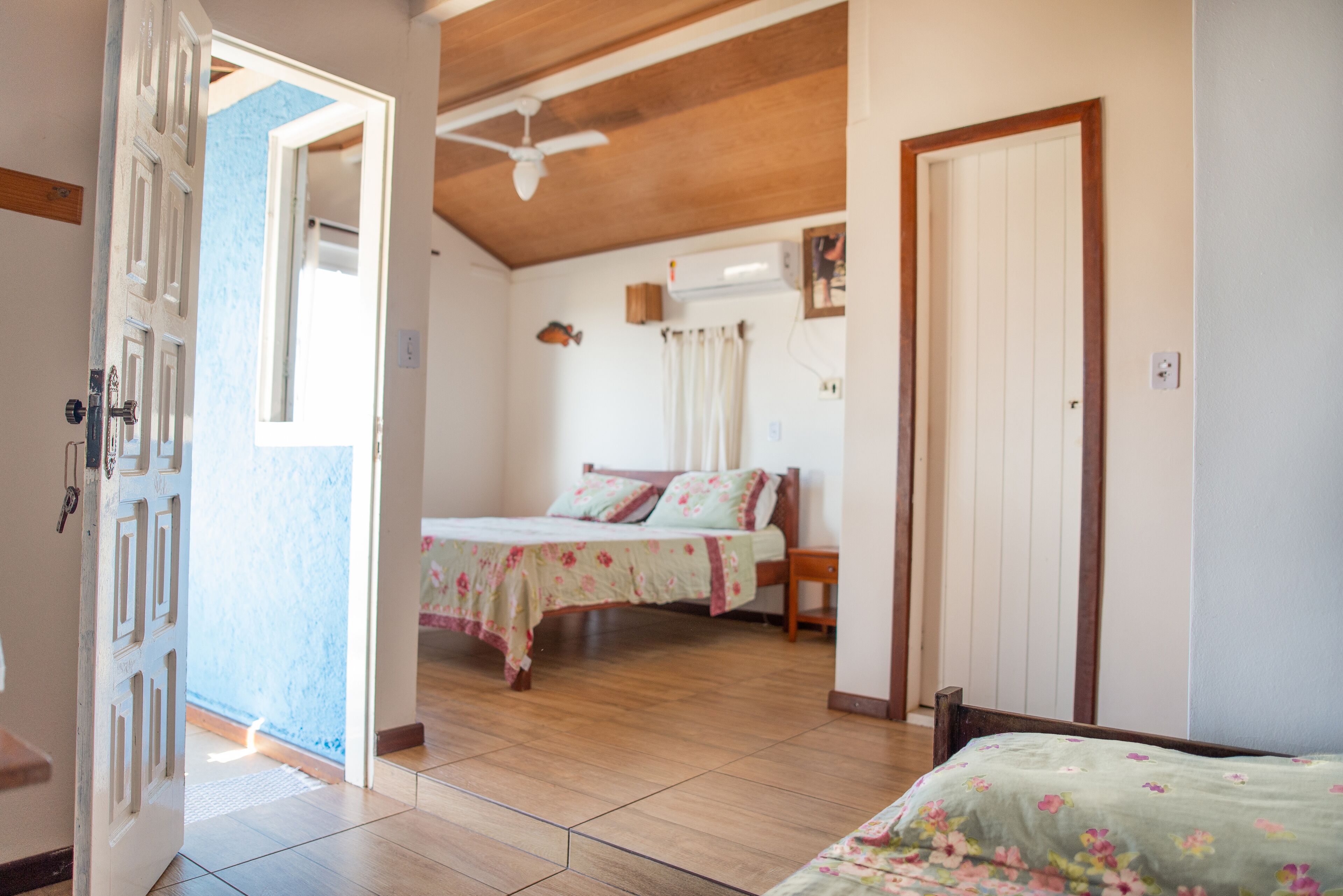Un dormitorio con una cama, techo de madera y una puerta.