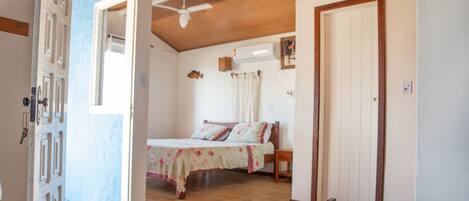 Un dormitorio con una cama, techo de madera y una puerta.