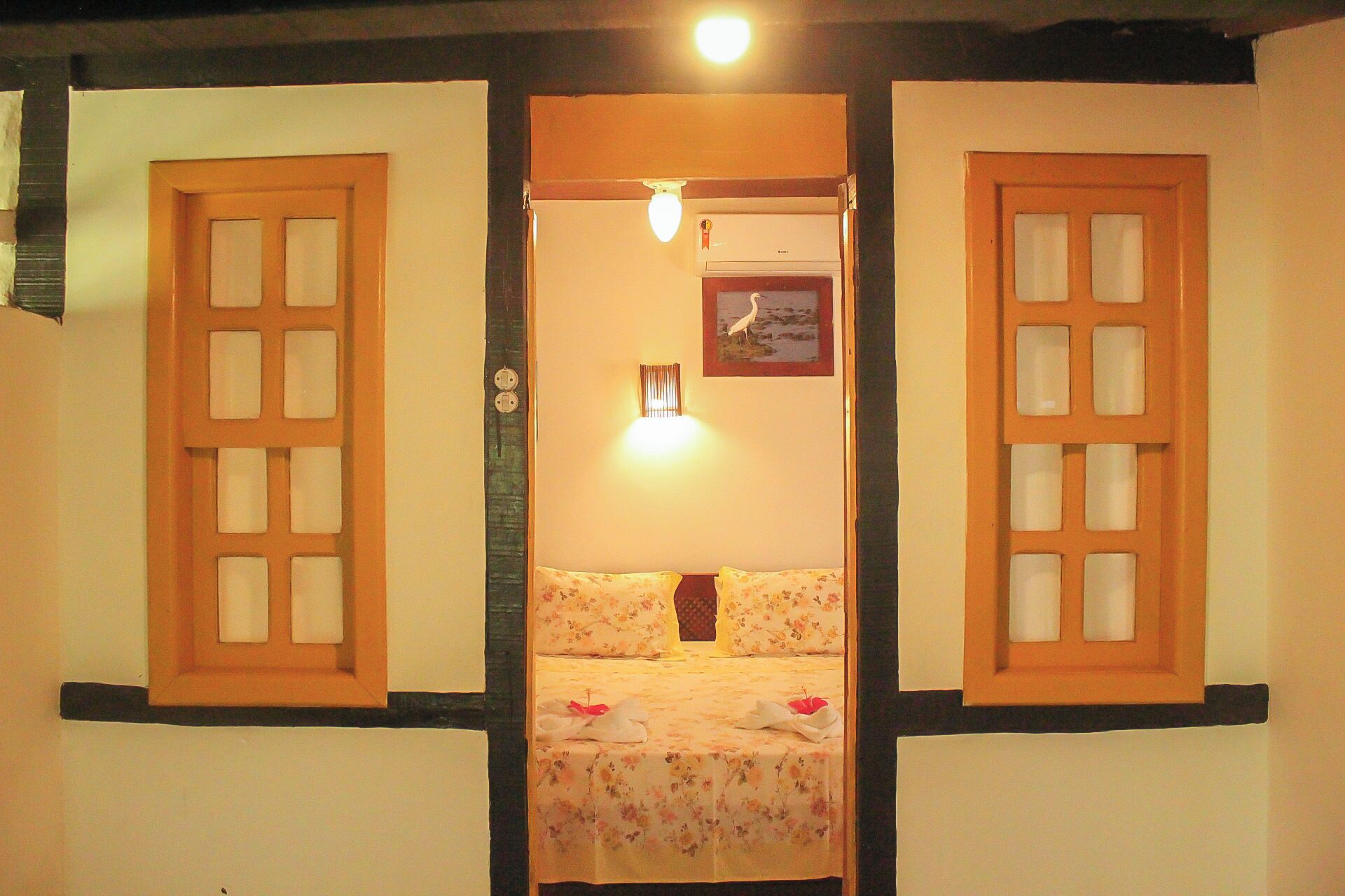 A room with a bed, a wall-mounted light, and a framed picture.