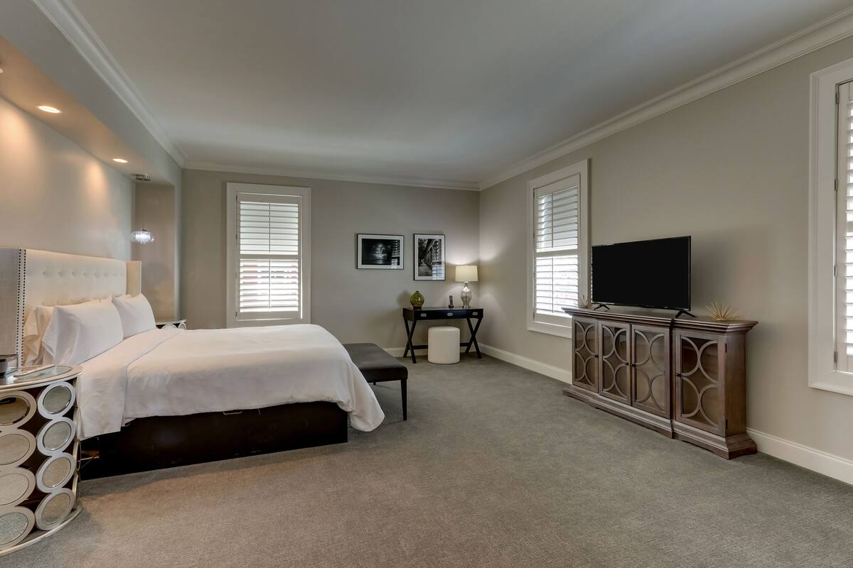 A bedroom with a bed, bedside table, lamp, TV, and a cabinet.