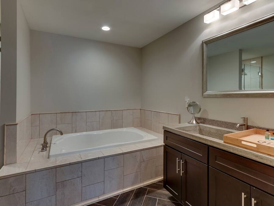 A modern bathroom with a freestanding bathtub, a large mirror, and a vanity with a tray of toiletries.