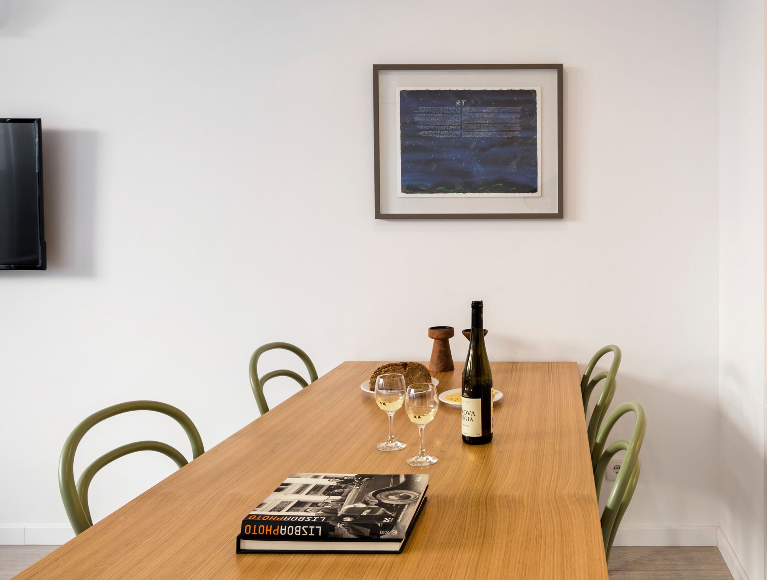A dining table with a wine bottle, glasses, and a book.