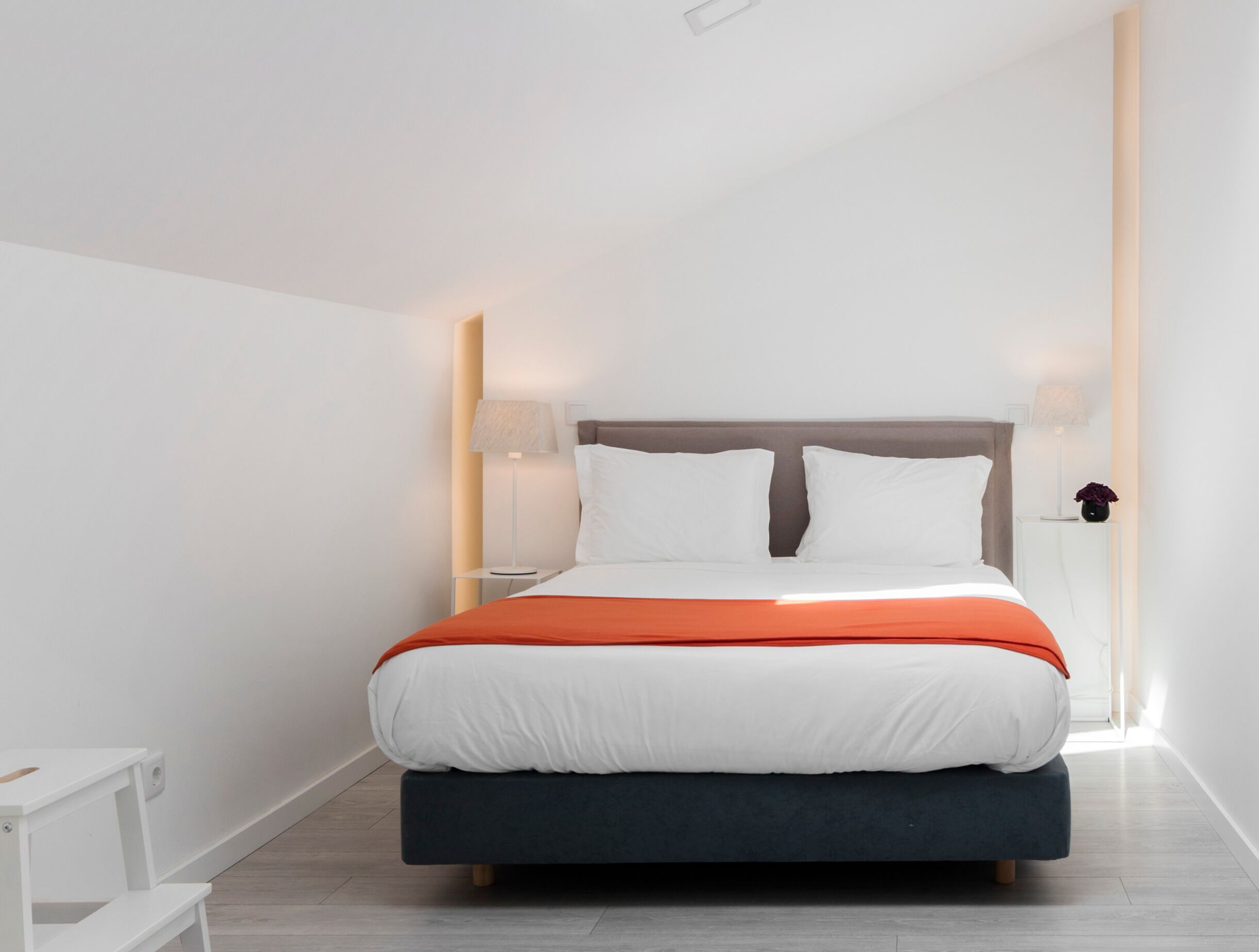 A modern bedroom with a bed, bedside lamps, and a nightstand.